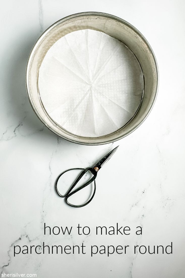 parchment paper circle in a round pan next to vintage scissors