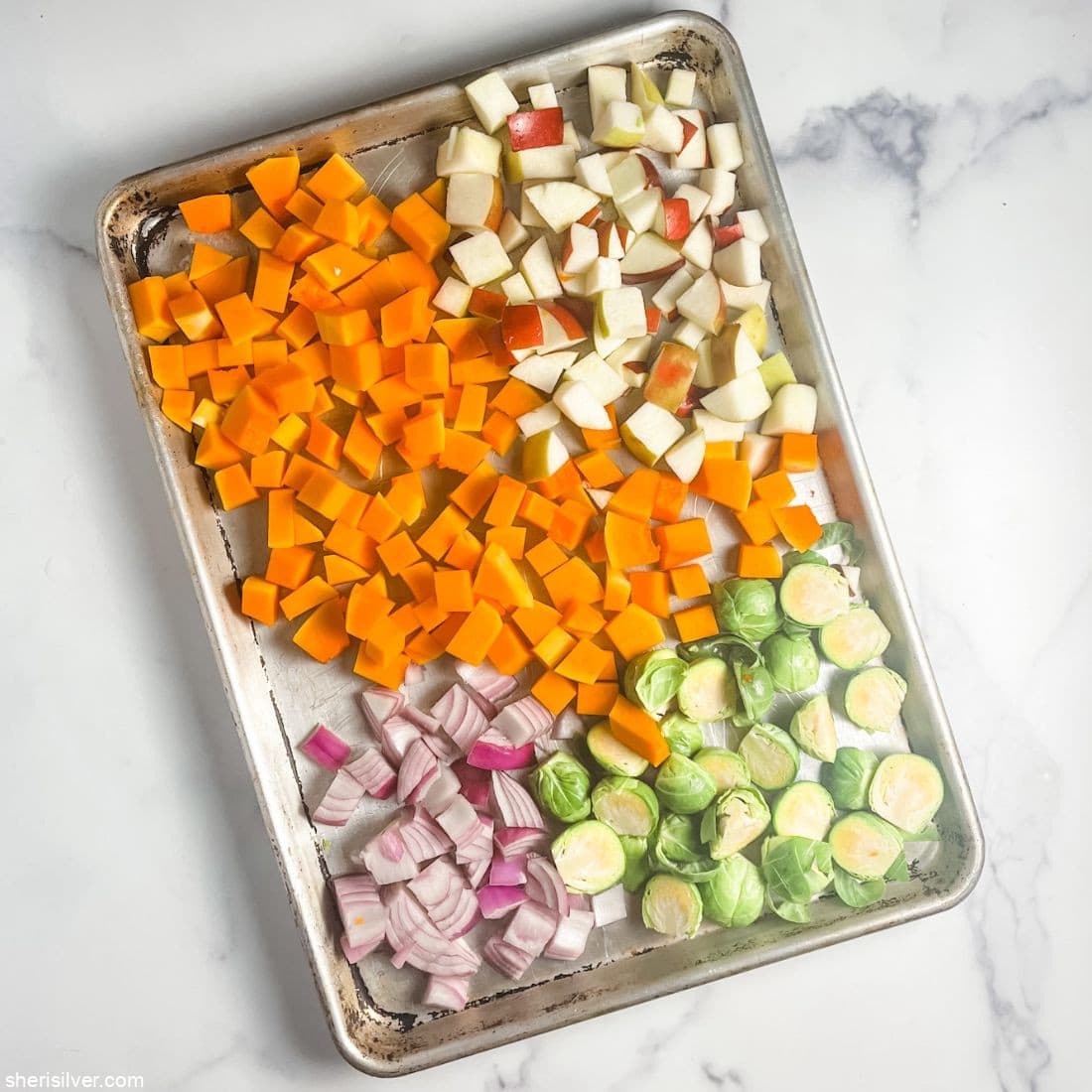 butternut squash chopped apples chopped red onion chopped brussels sprouts on a sheet pan