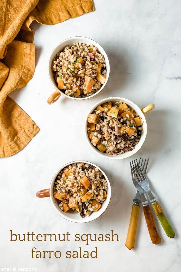 butternut squash farro salad in ceramic mugs next to vintage forks and linen napkin