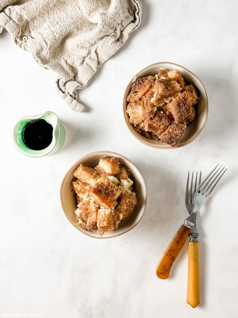french toast bake in ceramic bowls with vintage forks and a green pitcher of maple syrup