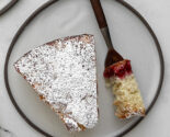 Overhead close-up of a slice of cranberry vanilla coffee cake with a forkful of cake beside it, showing the moist crumb and cranberry swirl.