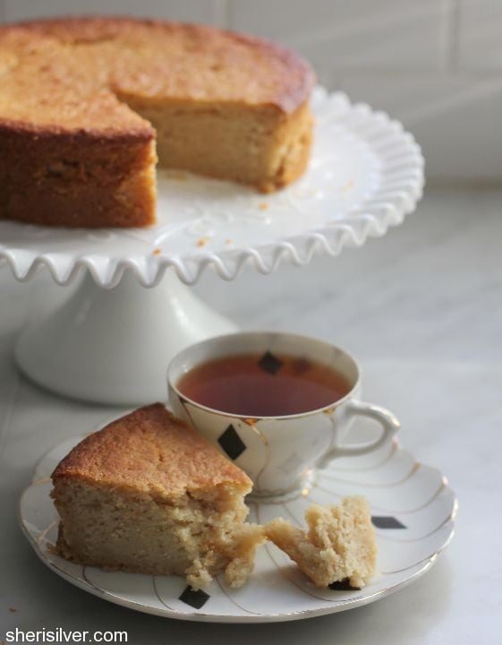honey lemon cake on a cake stand with a cup of tea