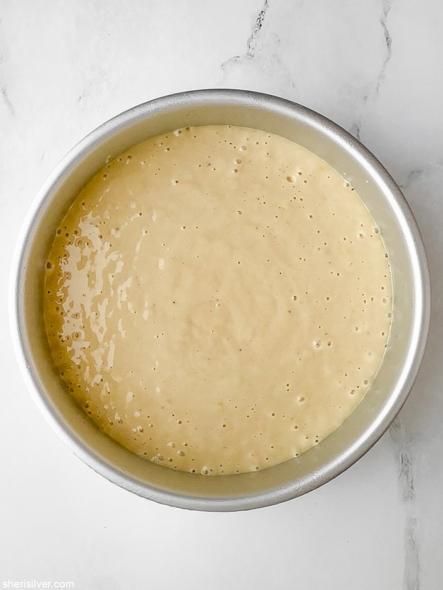 Honey lemon yogurt cake batter poured into an 8-inch round pan, ready to bake.