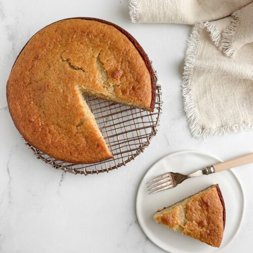 Honey lemon yogurt cake with a slice cut out and served on a white plate with vintage fork and linen napkin.