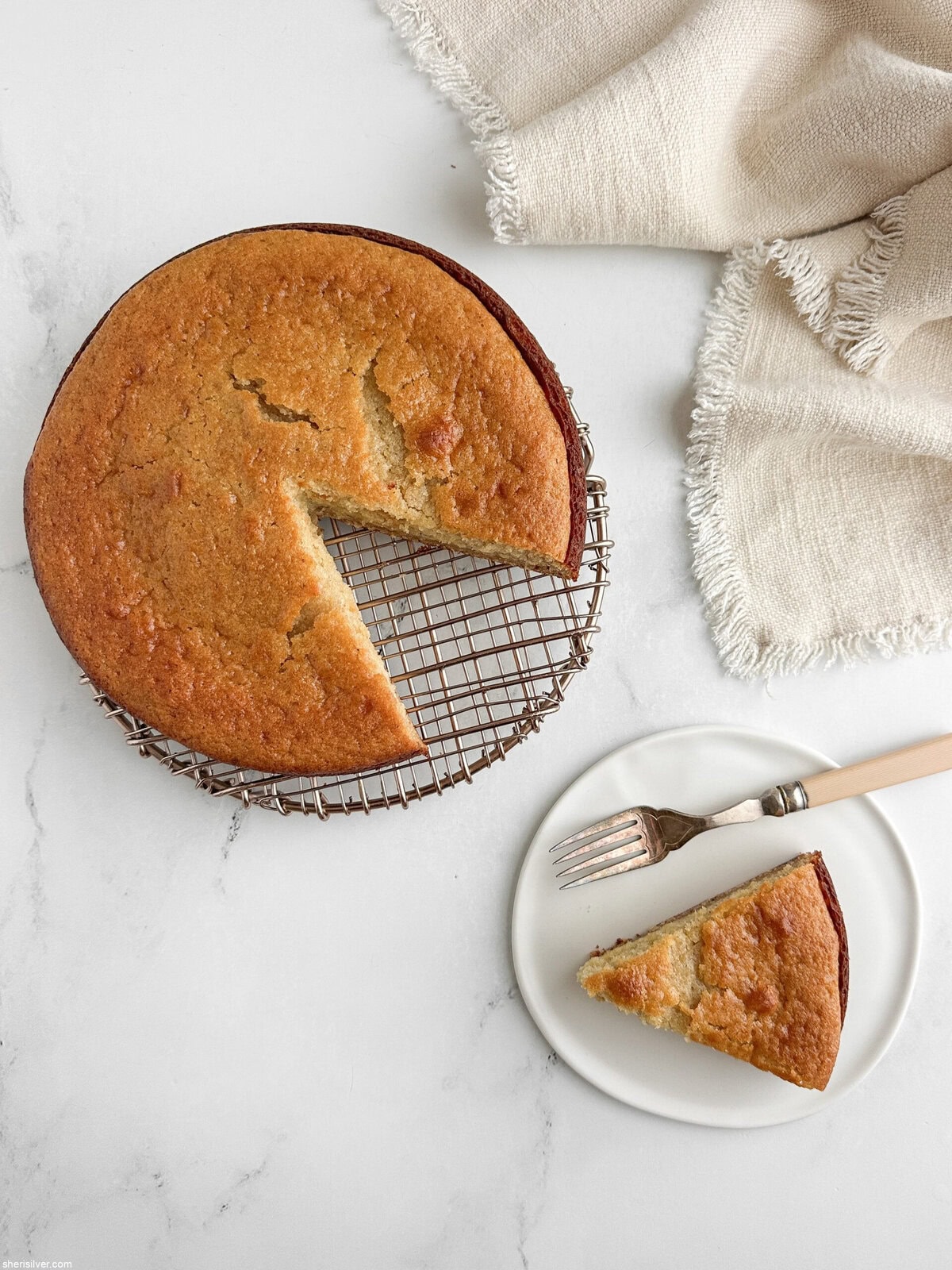Honey lemon yogurt cake with a slice cut out and served on a white plate with vintage fork and linen napkin.