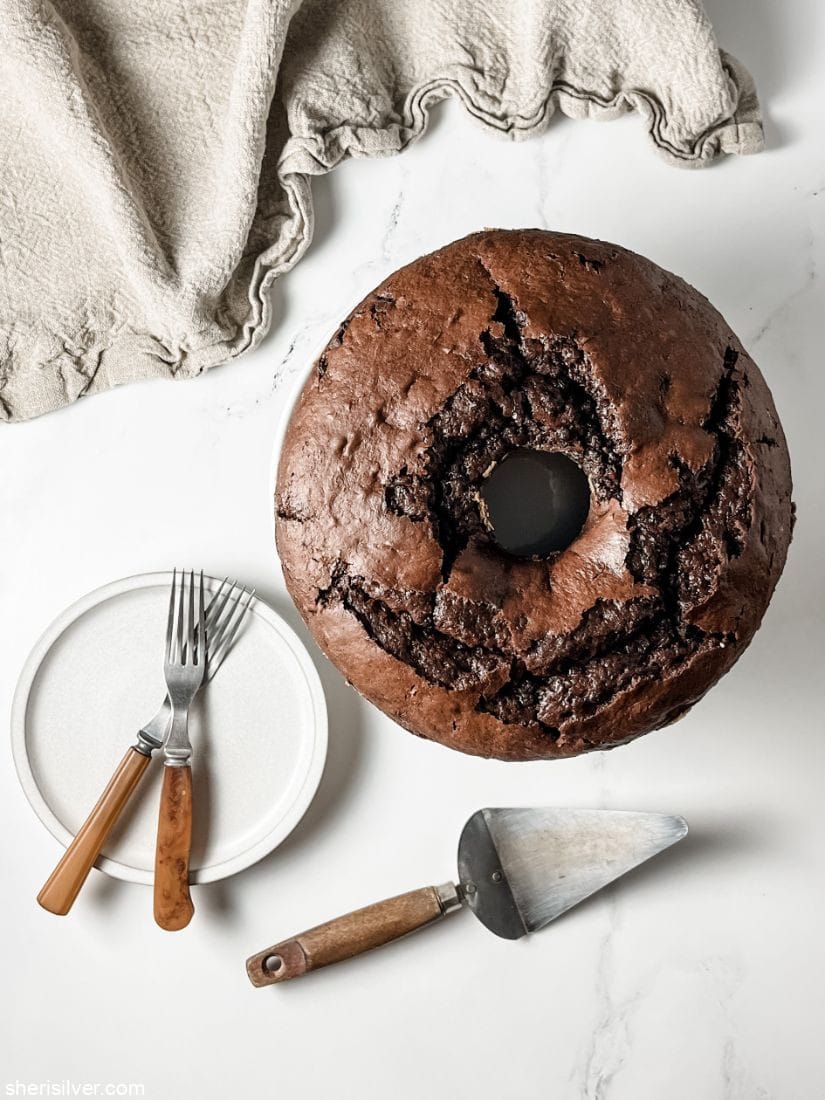 chocolate cake next to white plates and vintage forks