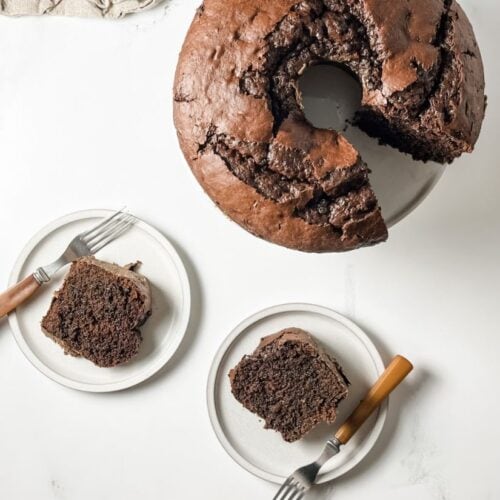 chocolate cake next to slices of chocolate cake on white plates
