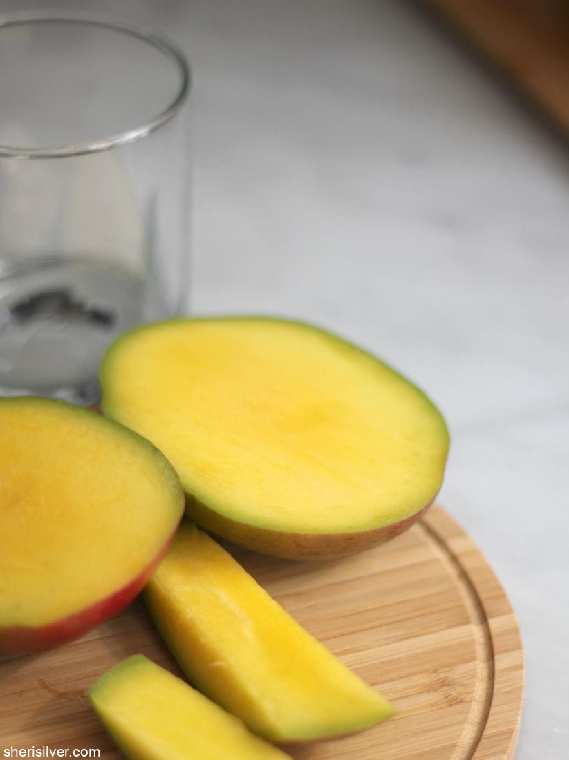cut mango and drinking glass on a wooden board
