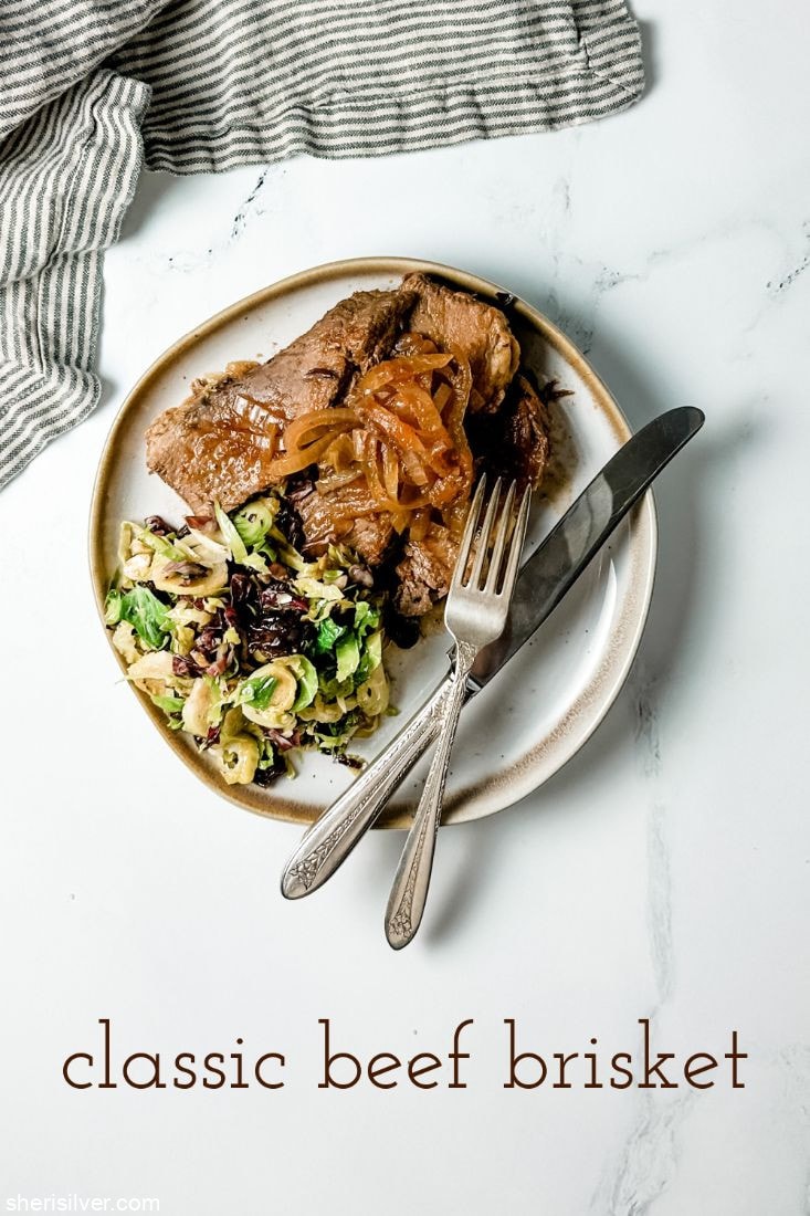 brisket with brussels salad on a ceramic plate with vintage silverware