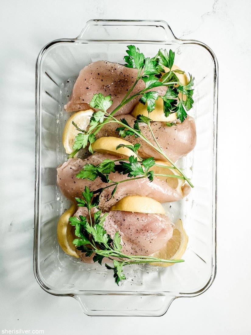 boneless chicken breasts with lemon and parsley in a glass baking dish