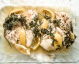 oven baked chicken breasts with lemon and parsley in a glass baking dish
