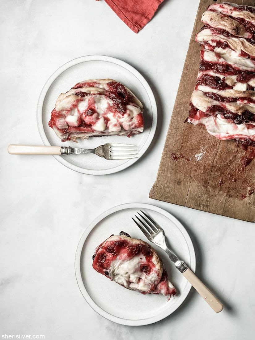cranberry brie pull apart loaf on a wooden board next to slices of loaf on white plates