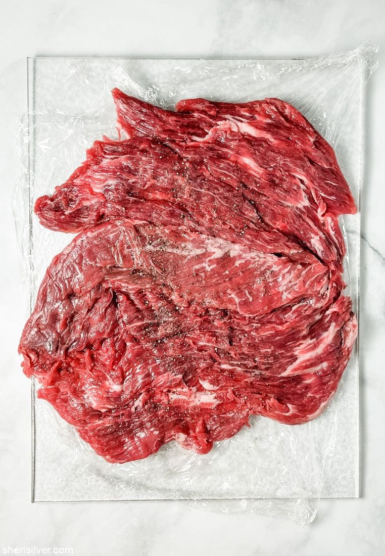 butterflied flank steak on a clear cutting board