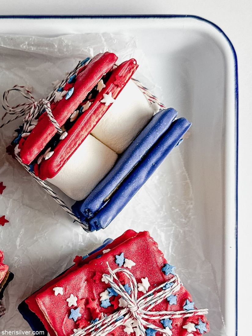red white and blue smores wrapped in bakery twine in a white enamel tray
