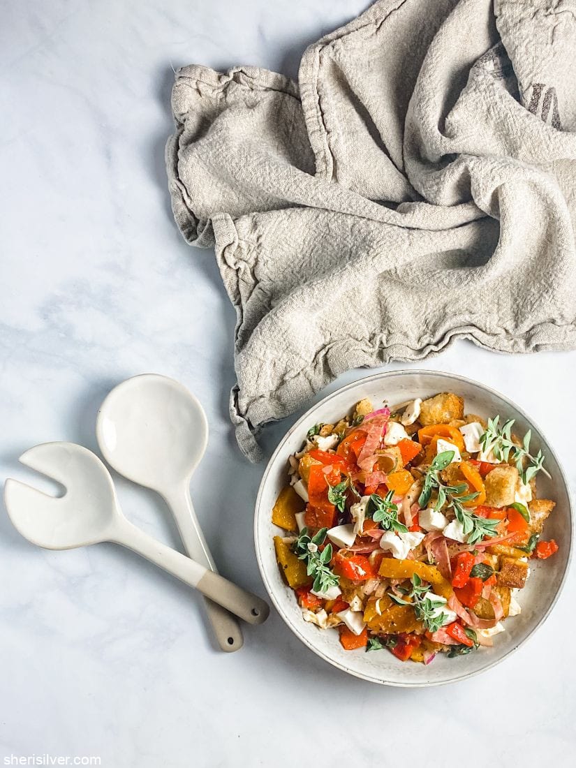 roasted pepper panzanella in a ceramic bowl with serving fork and spoon and linen napkin