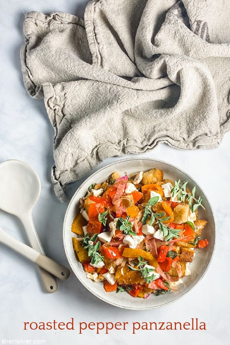 roasted pepper panzanella in a ceramic bowl with serving fork and spoon and linen napkin