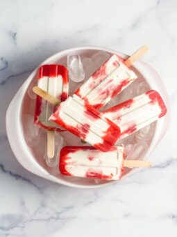 strawberries and cream popsicles in a bowl of ice