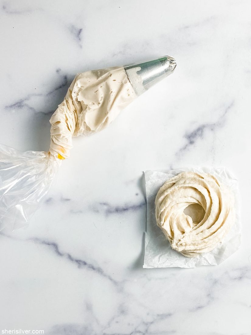 doughnut batter in pastry bag and on parchment paper