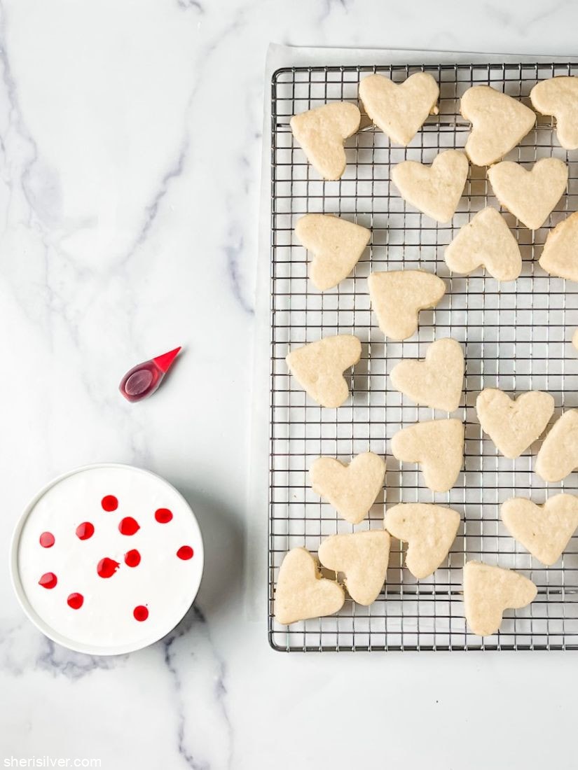heart sugar cookies on a wire rack with bowl of marbled royal icing
