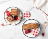 raspberry french toast roll ups on white plates with berries and maple syrup