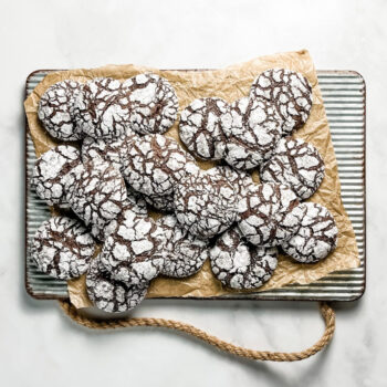 chocolate crinkle cookies on a parchment lined ribbed metal tray