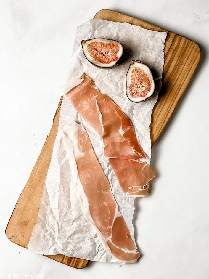 prosciutto and figs on a wooden cutting board