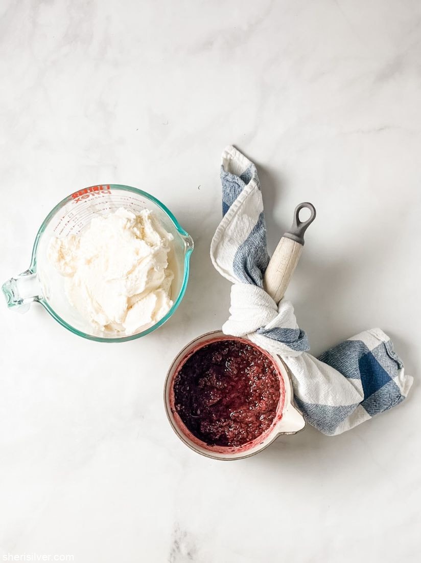 pyrex measuring cup filled whipped cream next to a pot of blackberry puree
