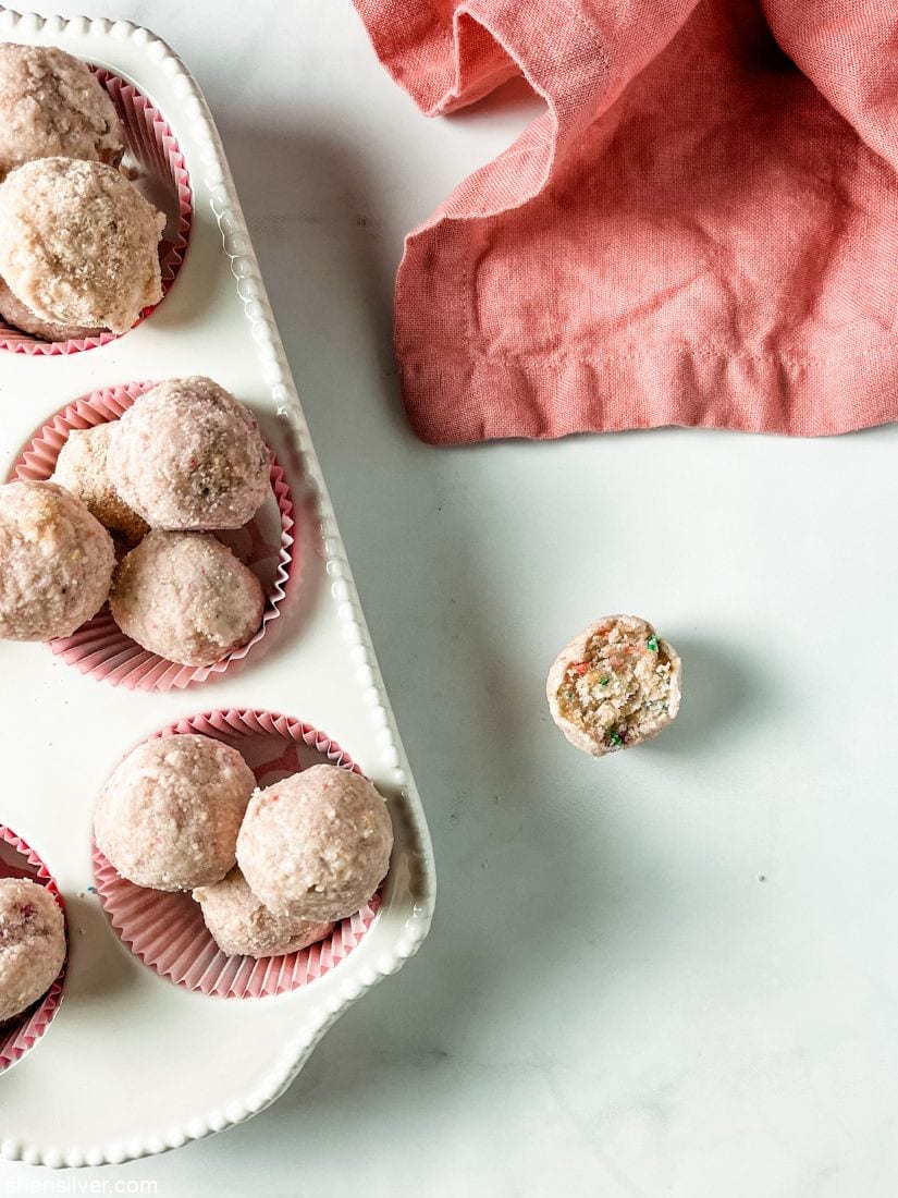 milk bar birthday cake truffles in a white ceramic muffin tin with pink linen napkin