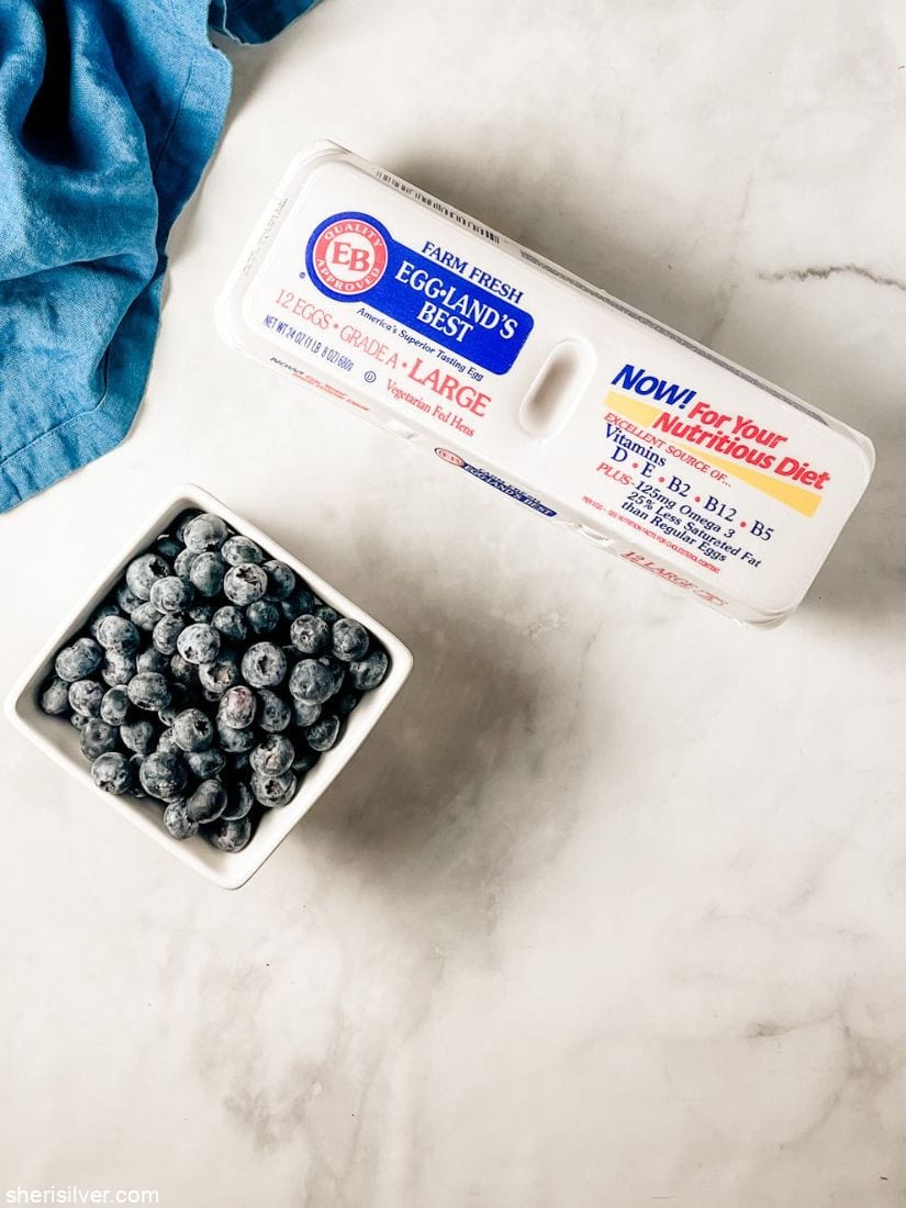 ceramic container with blueberries next to egg carton
