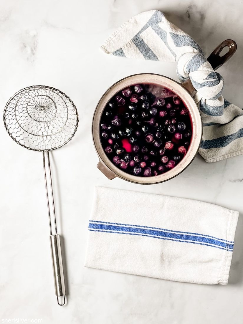 pot filled with blueberries next to a strainer and white napkin