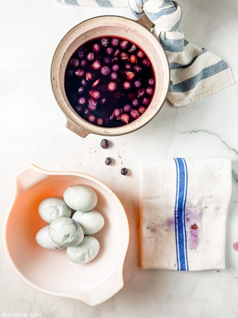 hard boiled eggs in a pyrex bowl next to a pot filled with blueberries