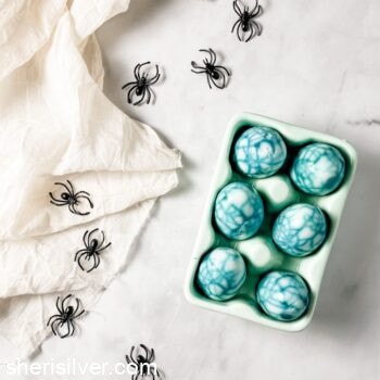 spider web eggs in a ceramic egg holder with plastic spiders and cheesecloth