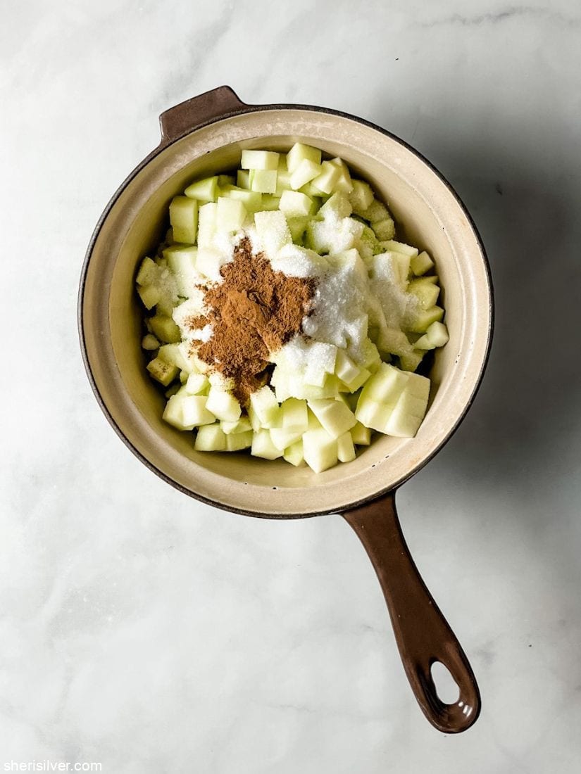 chopped apples granulated sugar and cinnamon in a ceramic saucepan