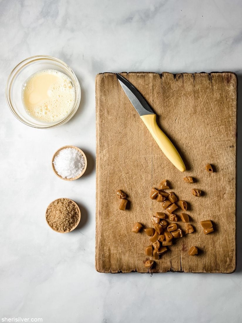chopped caramels on a wooden board with a yellow handled knife