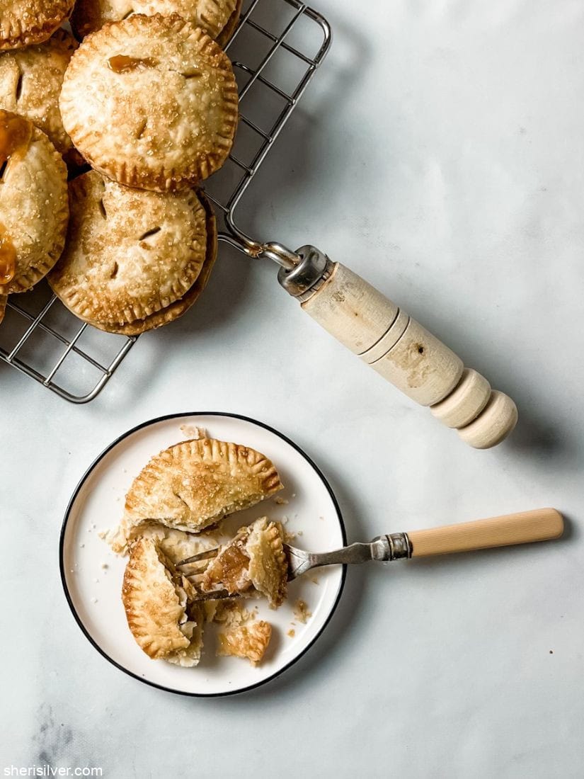 caramel apple hand pie on a ceramic plate next to pies on a cooling rack