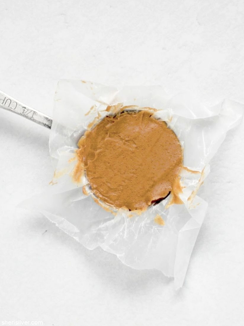 peanut butter in a metal measuring cup lined with wax paper