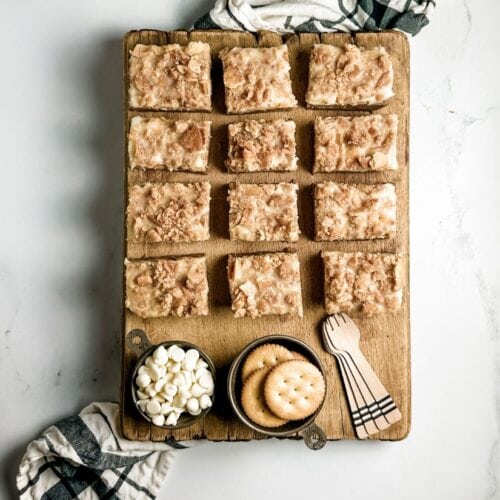 almond butter ritz crunch bars on a wooden board next to metal cups filled with ritz crackers and white chocolate chips