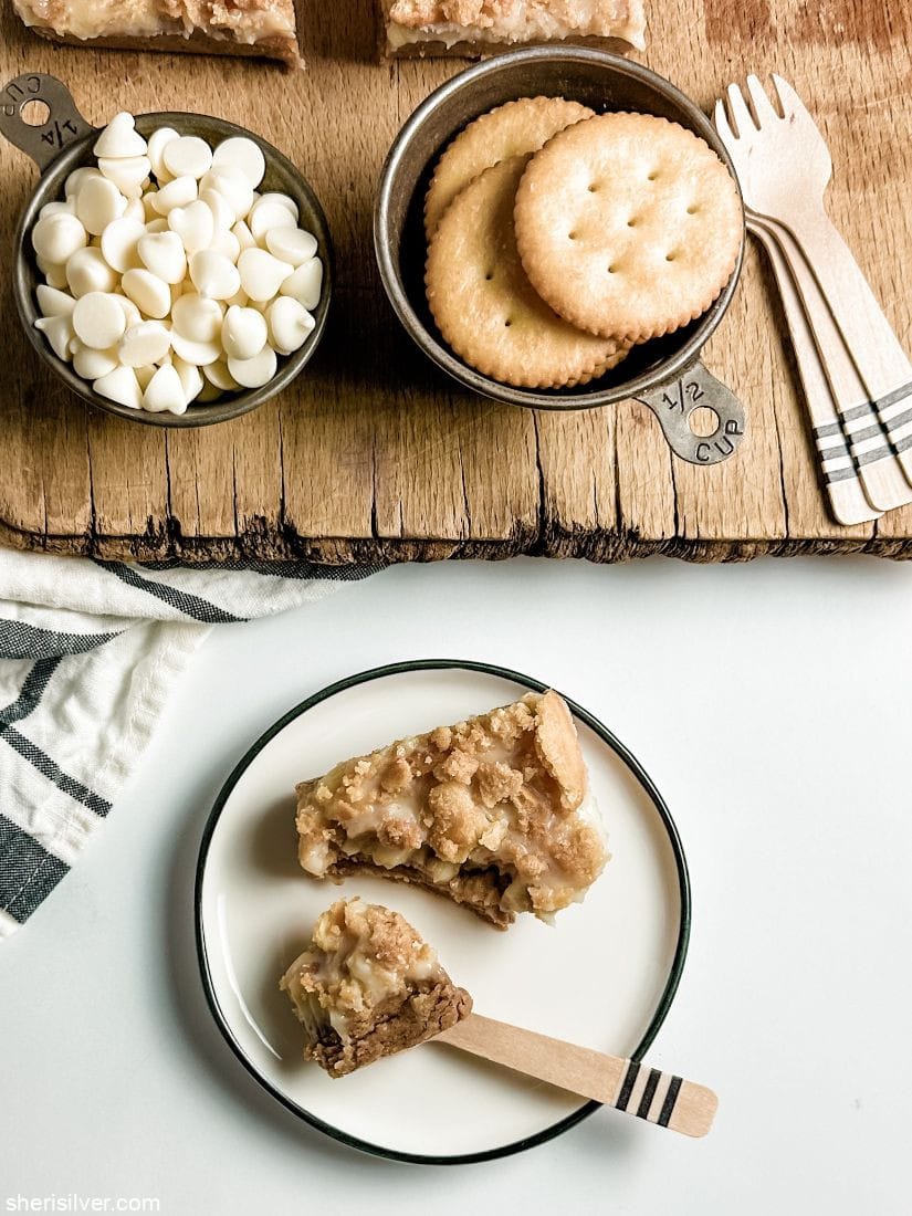 almond butter ritz crunch bars on a ceramic plate next to metal cups filled with ritz crackers and white chocolate chips