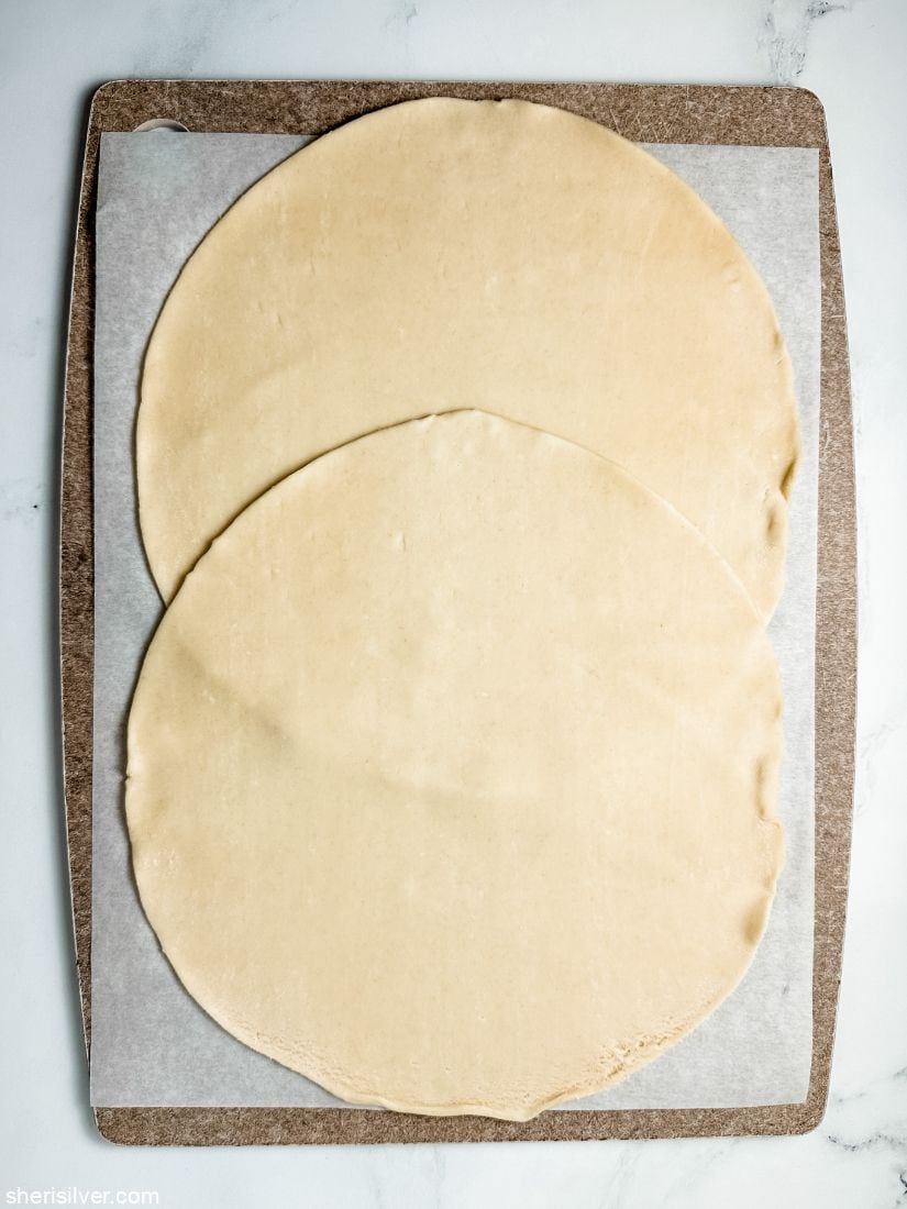 two round pie crusts on a sheet of parchment paper