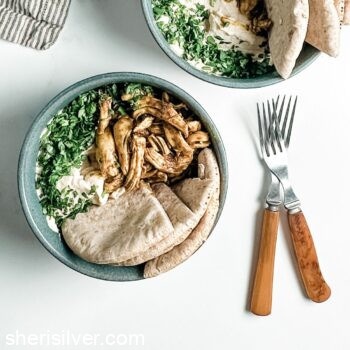 chicken hummus bowls in greay ceramic bowls with bakelite forks and a striped linen napkin