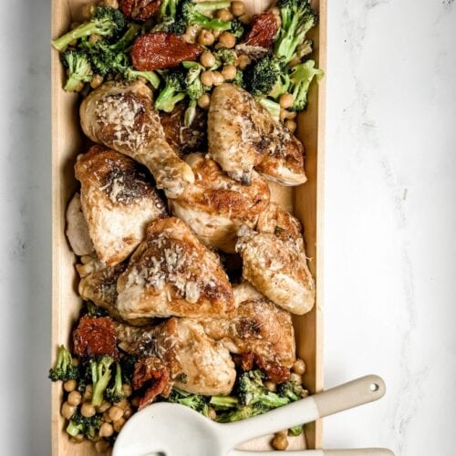 sheet pan chicken with broccoli and chickpeas in a wooden serving dish with ceramic serving spoons