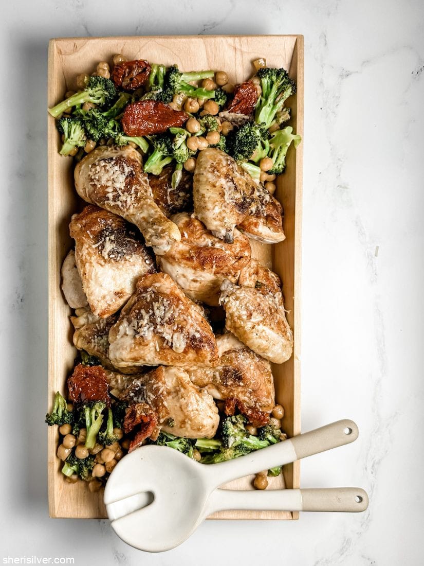 sheet pan chicken with broccoli and chickpeas in a wooden serving dish with ceramic serving spoons