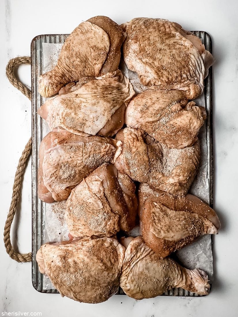 cut up chicken with spice rub on a ribbed metal tray