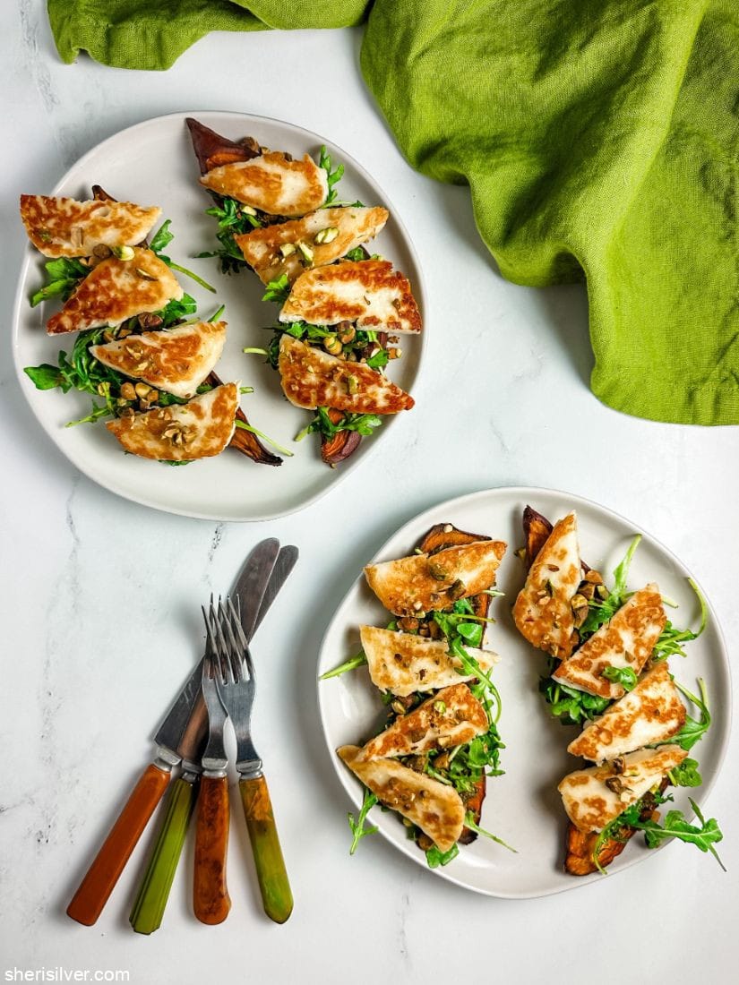 sweet potato toasts topped with arugula and halloumi on white plates next to vintage flatware