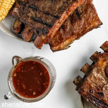 grilled ribs next to a jar of bbq sauce