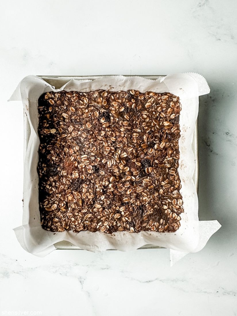 chocolate granola bar batter in a parchment lined baking pan