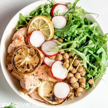 salmon with chickpeas and arugula in a white bowl