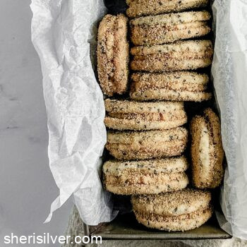 sesame sandwich cookies with tahini frosting in a parchment lined loaf pan