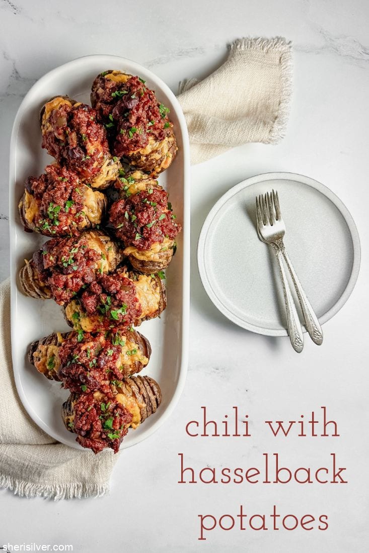 chili with hasselback potatoes on a white platter