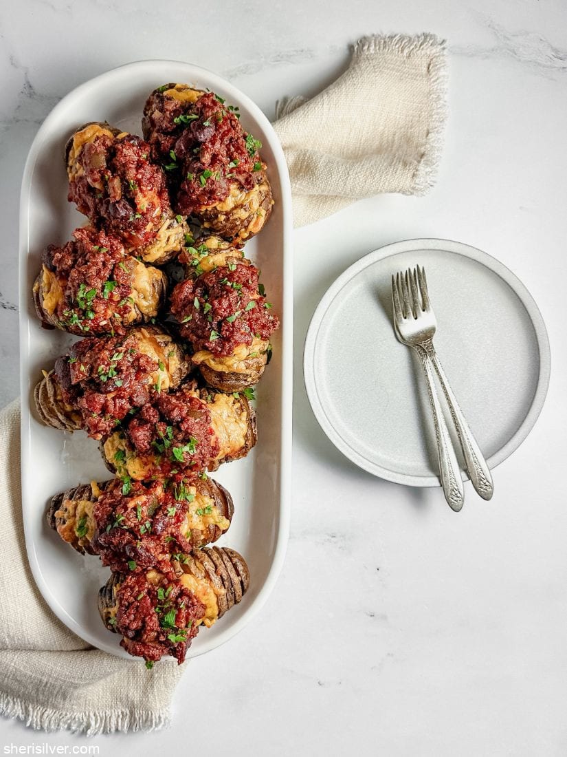 chili with hasselback potatoes on a white platter